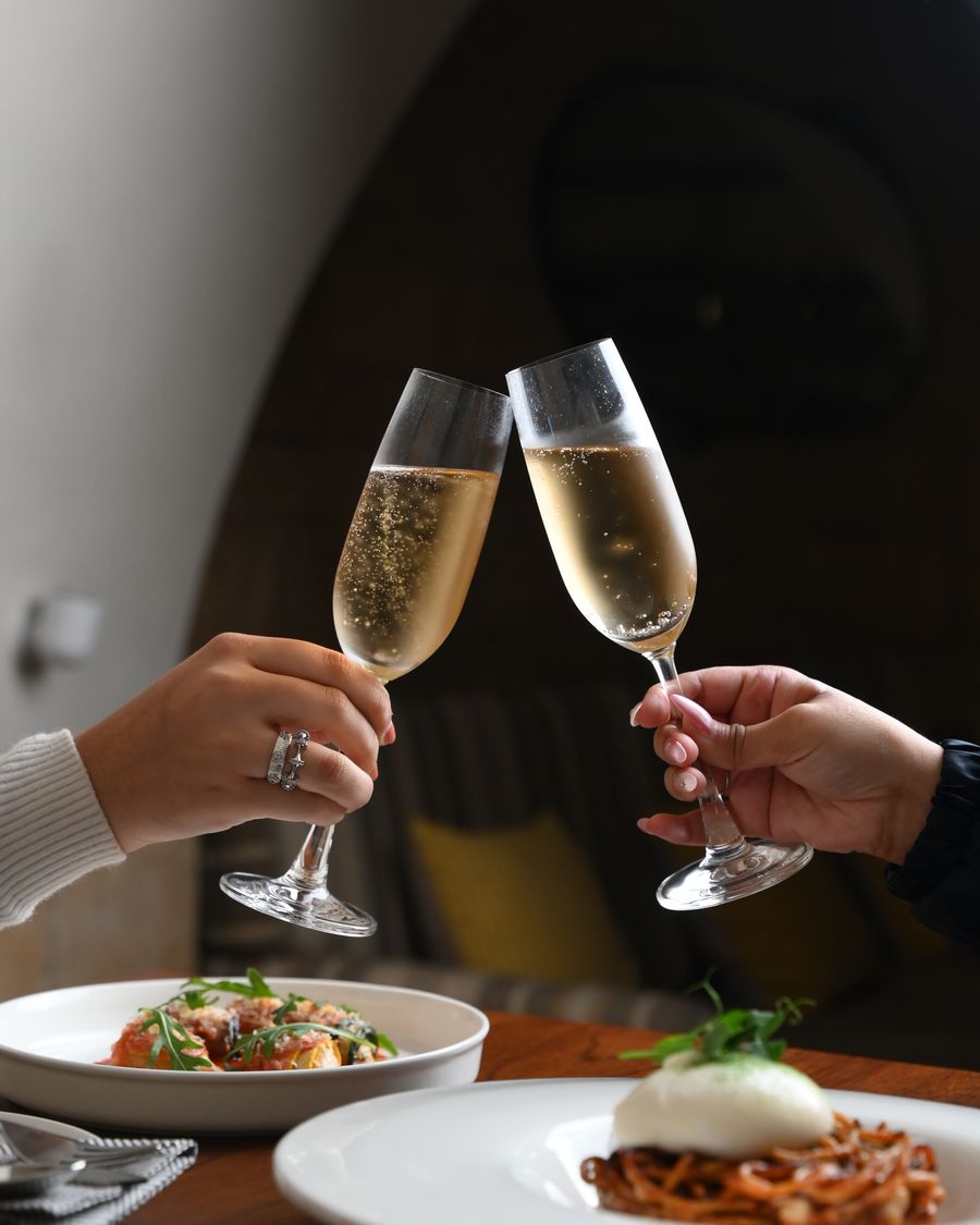 A toast raised at a banquette table beneath the stone arch