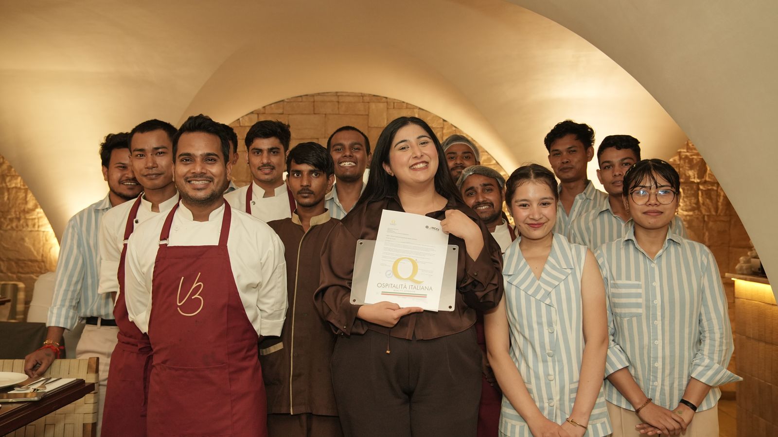 The Via Bianca team gathered under the arch with the Ospitalità Italiana certificate