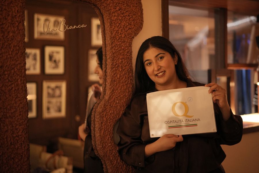 Chef Kamalika Anand holding the Ospitalità Italiana plaque in the dining room