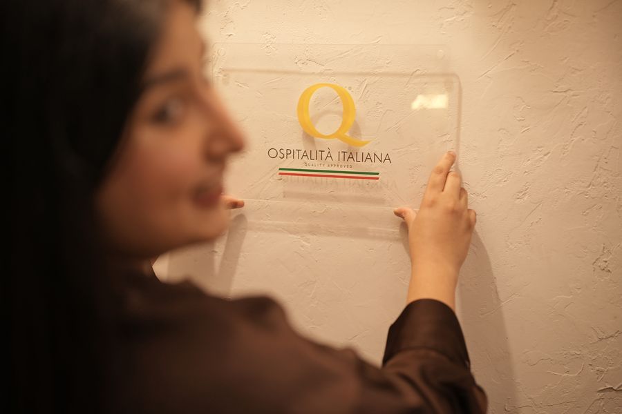The Ospitalità Italiana plaque being mounted on the restaurant wall