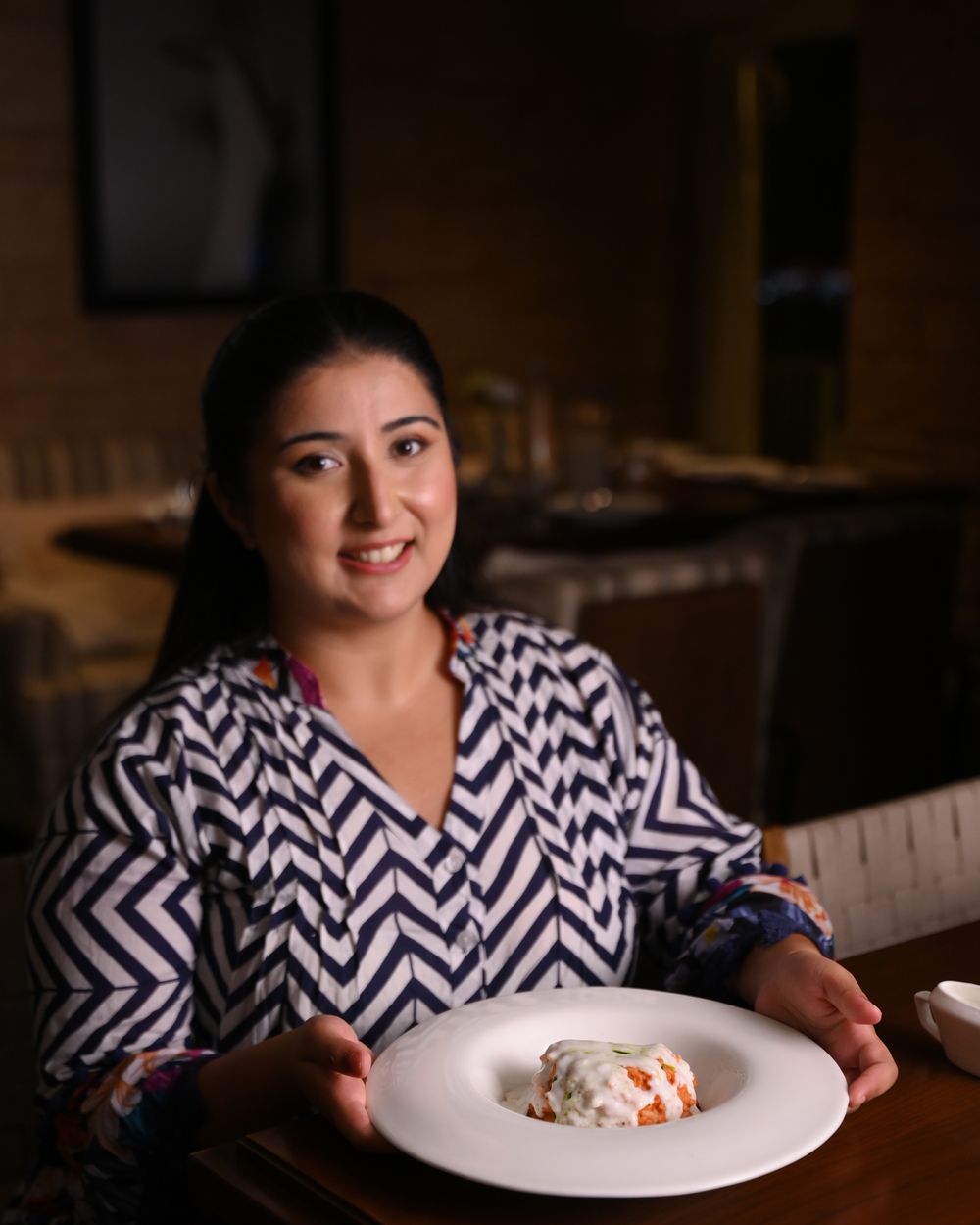 Chef Kamalika Anand presenting a dish in the dining room