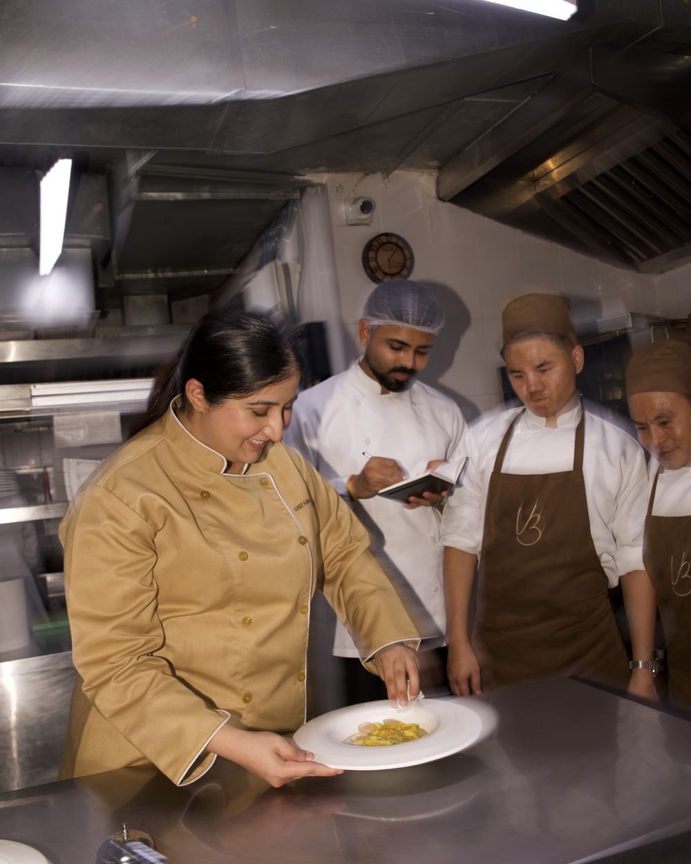 Chef Kamalika Anand plating alongside the kitchen brigade