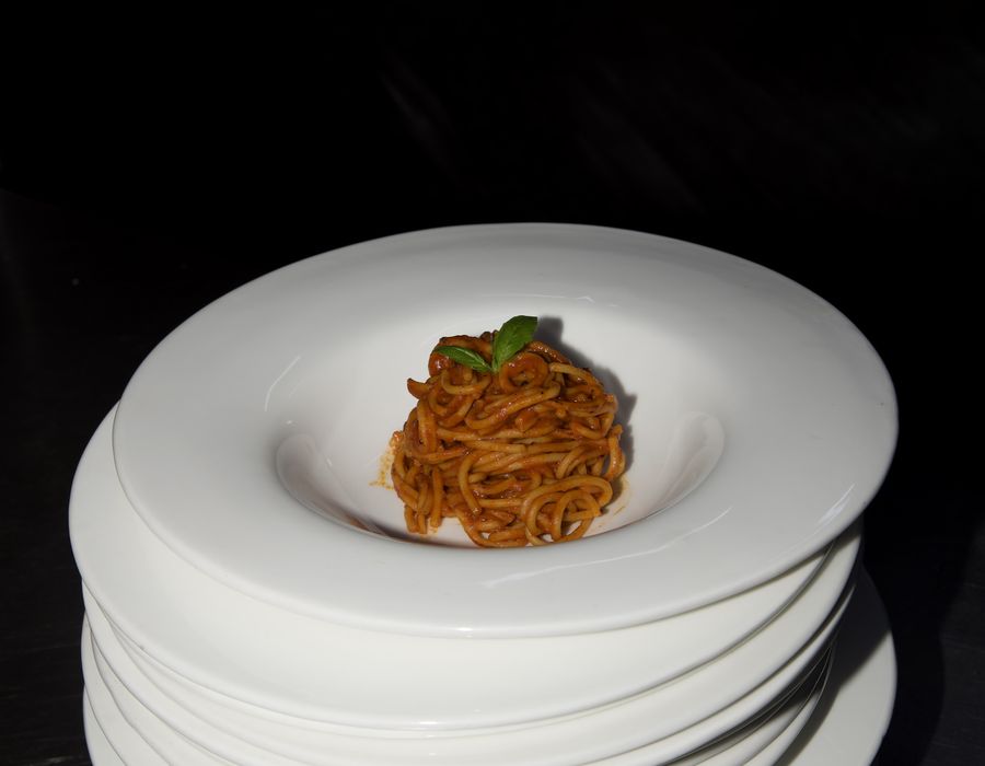 A single portion of pasta plated on a stack of white bowls
