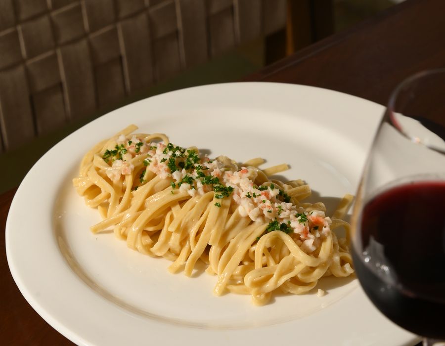 Fresh tagliatelle finished at the table with a glass of red wine