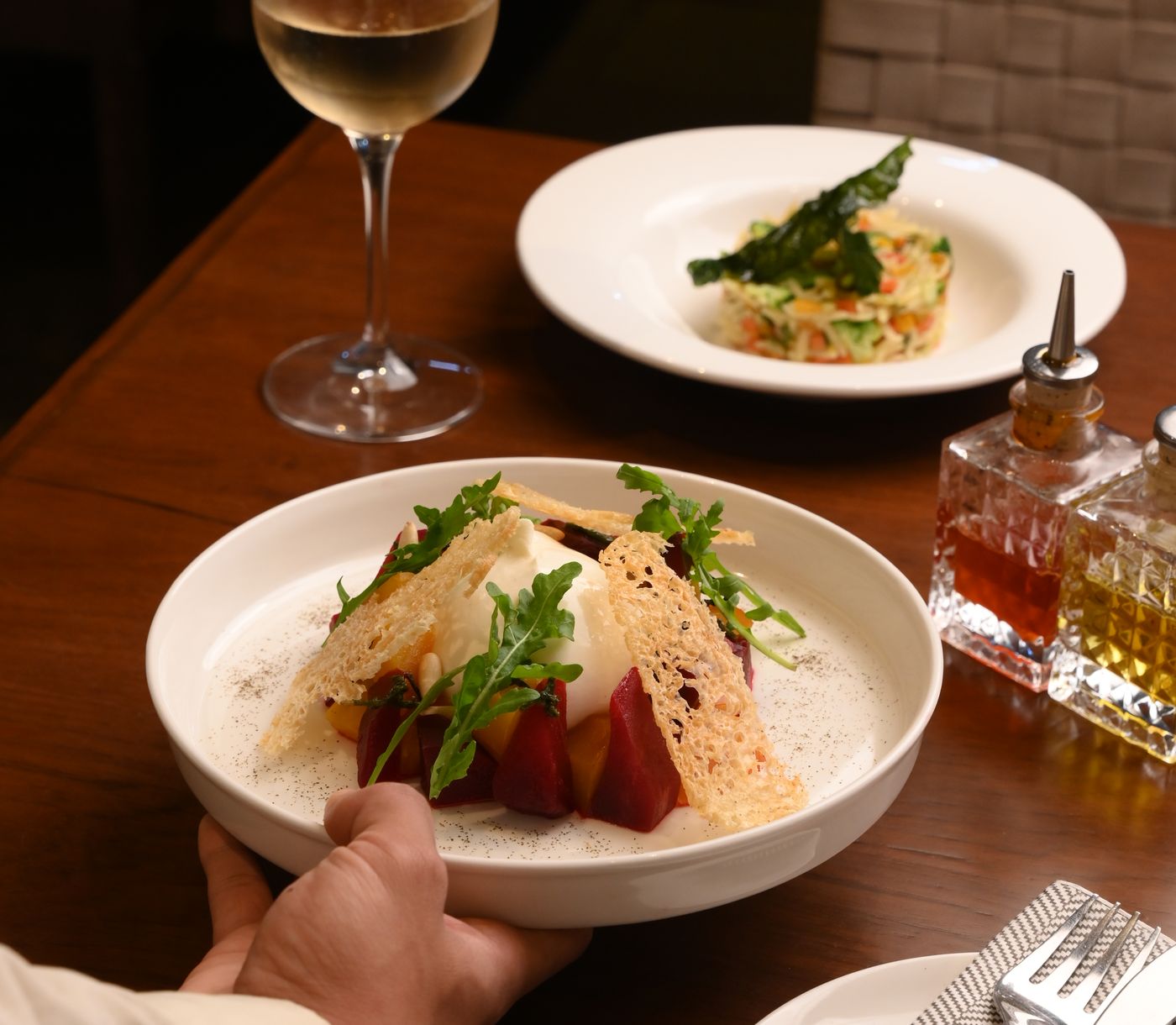 A laid table with wine and two plates being set down