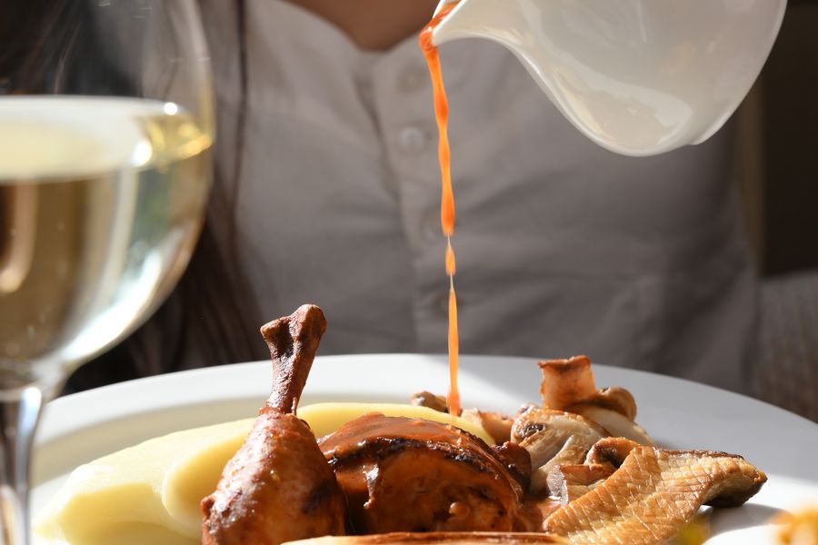 Sauce poured over a plated quail with mash